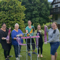 Auf dem Bild sind 5 Frauen die ihre gefärbte Wolle in die Kamera halten.