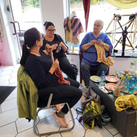 Frauen die in einer gemütlichen Runde stricken während die Wolle gefärbt wird.